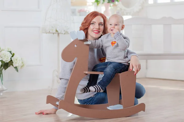 Felice carino piccolo ragazzo equitazione in legno cavallo a dondolo mamma — Foto Stock