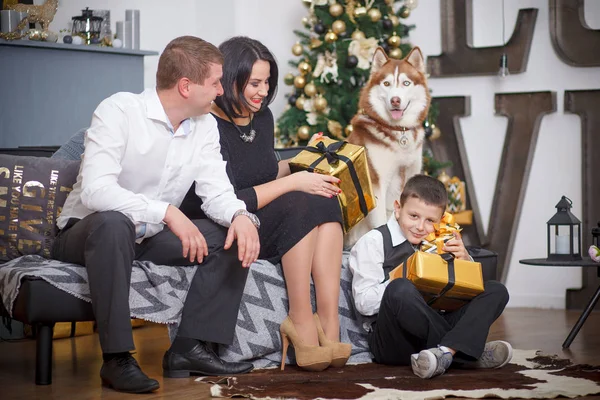 Família feliz e um cão Husky siberiano em torno da árvore de Natal — Fotografia de Stock