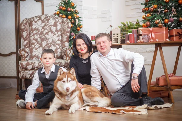 Madre, padre y niño pequeño con Husky fondo árbol de Navidad — Foto de Stock