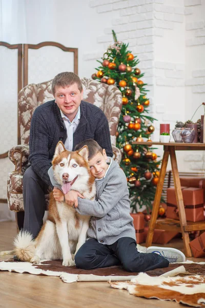 Padre y niño pequeño con Husky fondo árbol de Navidad — Foto de Stock