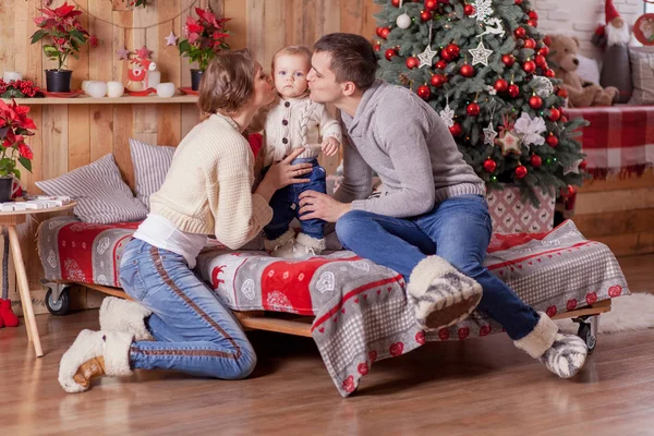 Familia feliz en una cama cerca del árbol de Navidad en casa — Foto de Stock