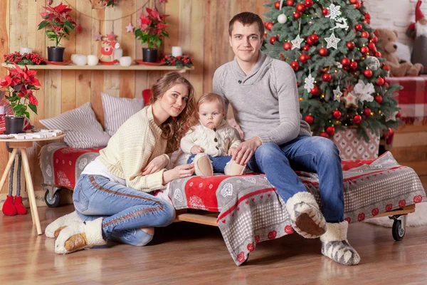 Ευτυχισμένη οικογένεια σε ένα κρεβάτι κοντά στο χριστουγεννιάτικο δέντρο στο σπίτι — Φωτογραφία Αρχείου