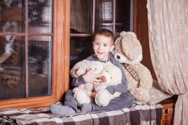 Hayalci çocuk Noel süsüyle pencere eşiğinde oturuyor.