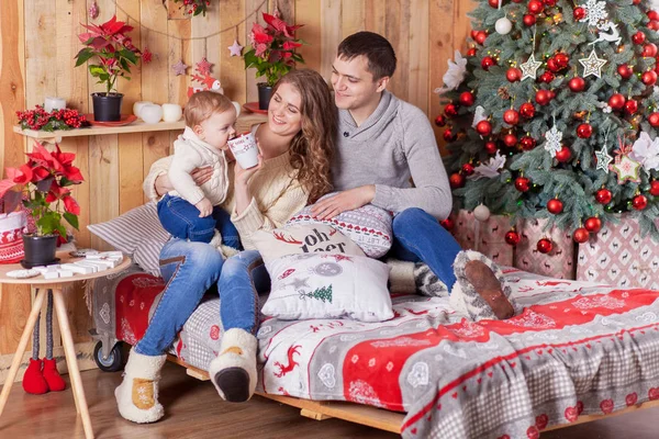 Noel ağacı evde yakınındaki bir yatakta mutlu aile