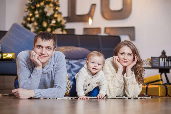 Familia feliz está acostado en el árbol de la alfombra y sonriendo —  Fotos de Stock