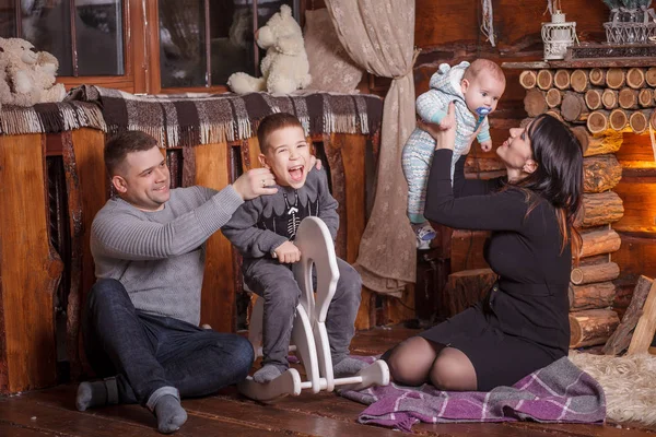 Familia joven con dos niños cerca de la chimenea celebrando la Navidad — Foto de Stock