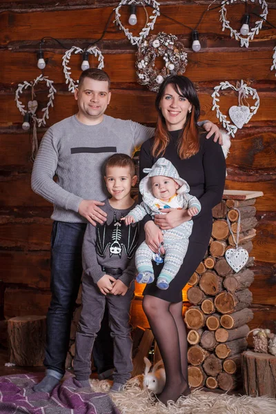 Familia joven con dos niños cerca de la chimenea celebrando la Navidad —  Fotos de Stock