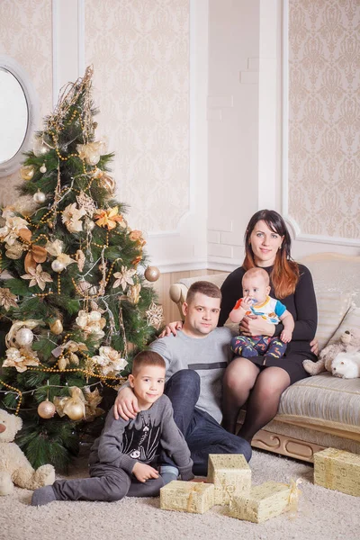 Семья, сидящая у елки — стоковое фото