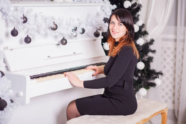 Charming brunette with long hair in evening dress playing piano. — Stock Photo, Image