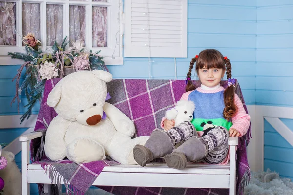 Menina sentada no banco com brinquedos — Fotografia de Stock