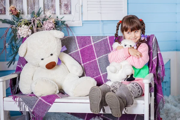 Menina sentada no banco com brinquedos — Fotografia de Stock