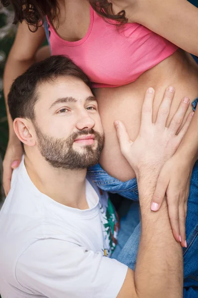 Yakışıklı adam, güzel hamile karısının karın için dinleme — Stok fotoğraf