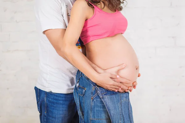 Feliz pai de família e mãe grávida e perto de uma parede de tijolo em branco no quarto — Fotografia de Stock