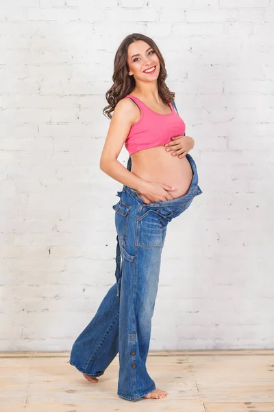 Mujer embarazada de pie sosteniendo su vientre —  Fotos de Stock