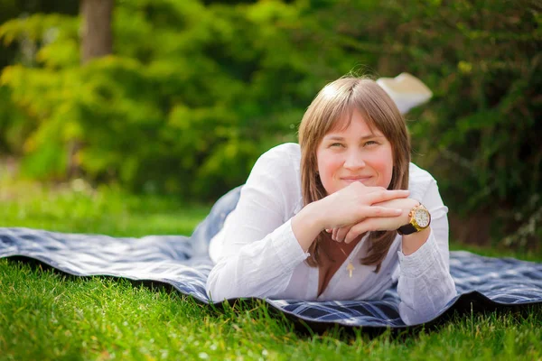 Glücklich schöne junge Frau sitzt auf einer Bank in einer Sommerstraße — Stockfoto