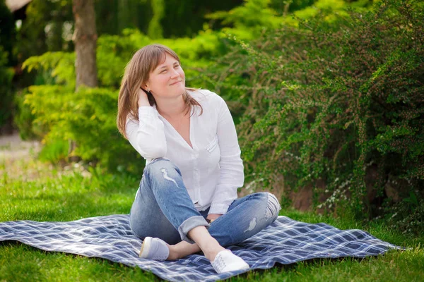 Eine Frau sitzt auf dem Gras im Park — Stockfoto