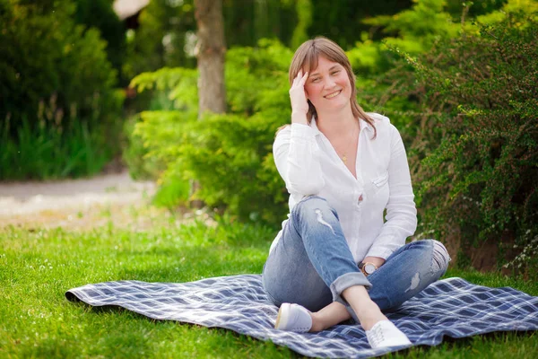 En kvinna sitter på gräset i parken — Stockfoto