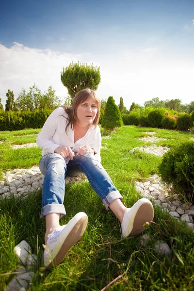 Een vrouw zit op het gras in het park — Stockfoto