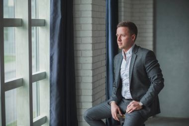 Belgili tanımlık pencere eşiği yanında duran genç adam