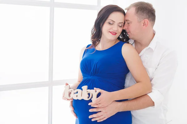 Молодой человек обнимает красивую беременную девушку — стоковое фото