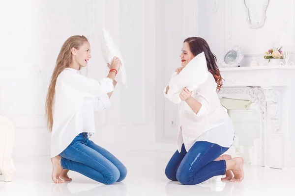 Mom and daughter play with pillows fight