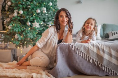 Anne, Noel ağacı evinin yanında kızını kucaklıyor.