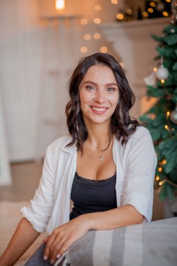 Güzel genç bir kadın yatak odasındaki Noel ağacının yanında.