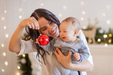 Genç anne ve küçük oğlu Noel oyuncakları oynuyorlar.