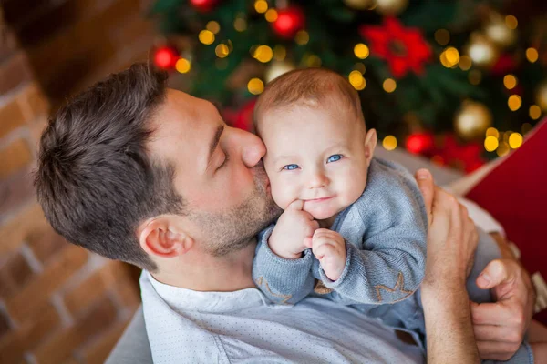 dad hugs newborn son christmas lights