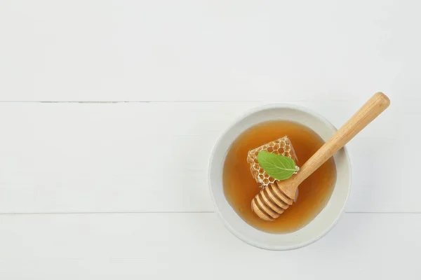 Miel fresca en el plato con panal y cazo de abeja sobre madera blanca — Foto de Stock