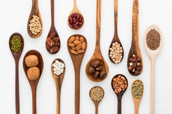 Different kind of beans and lentils in wooden spoon on white woo — Stock Photo, Image