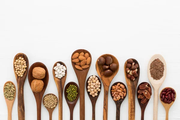 Different kind of beans and lentils in wooden spoon on white woo — Stock Photo, Image