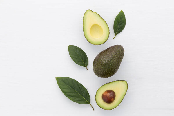 Slices of avocado on white background. Whole and half with leave