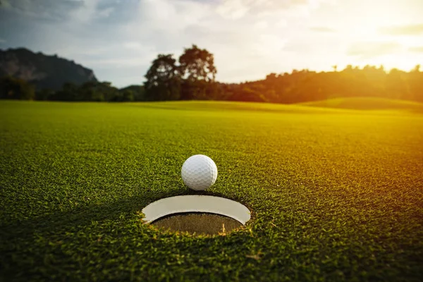 Selective focus. white golf ball near hole on green grass good f — Stock Photo, Image