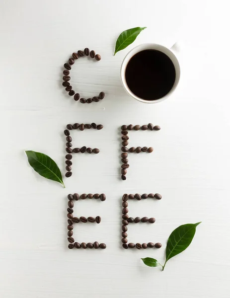 Творческая надпись кофе из жареных бобов, чашку кофе и — стоковое фото