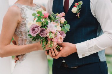 Gelin ve damat düğün buketi tutuyorlar.