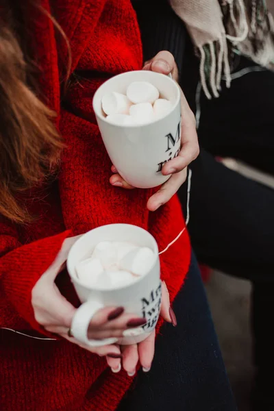 Lovers hold cups of cocoa in their hands