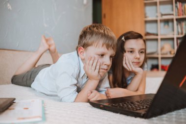 CoVid-19 karantinası sırasında evde dizüstü bilgisayarda webinar izleyen kız ve oğlan, bilgisayarla uzaktan öğrenme, okul için ödev yapan bir çocuk. Çocuklar evde kaldı. Evde eğitim