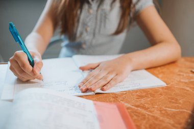 Kız evde CoVid-19 karantinası sırasında bir deftere ödev yazıyor. Uzaktan öğrenmeyi bilgisayarla yapıyor. Okul için ödev yapan bir çocuk. Çocuklar evde kaldı. Kız Kiril alfabesiyle yazıyor.