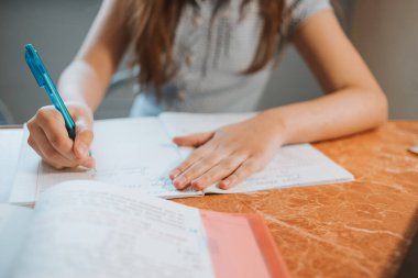 Kız evde CoVid-19 karantinası sırasında bir deftere ödev yazıyor. Uzaktan öğrenmeyi bilgisayarla yapıyor. Okul için ödev yapan bir çocuk. Çocuklar evde kaldı. Kız Kiril alfabesiyle yazıyor.