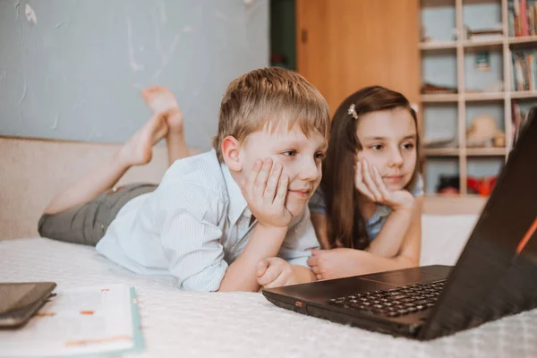 CoVid-19 karantinası sırasında evde dizüstü bilgisayarda webinar izleyen kız ve oğlan, bilgisayarla uzaktan öğrenme, okul için ödev yapan bir çocuk. Çocuklar evde kaldı. Evde eğitim
