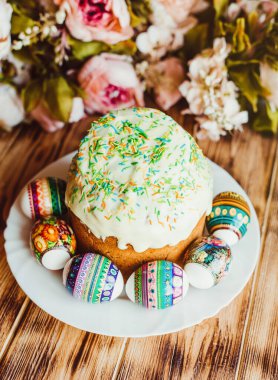 Renkli tozla süslenmiş ve ahşap arka planda renkli yumurtalarla süslenmiş paskalya pastası. Mutlu Paskalyalar. Dikey Fotoğraf