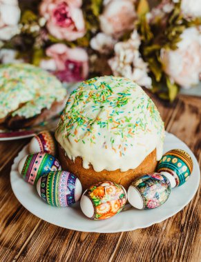 Renkli tozla süslenmiş ve ahşap arka planda renkli yumurtalarla süslenmiş paskalya pastası. Mutlu Paskalyalar. Dikey Fotoğraf