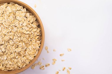 Tabakta yulaf ezmesi ve beyaz bir arka plana serpilmiş. Uzayı kopyala Düz Yatay