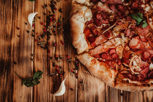 Tahta bir arka planda salamlı ve mozzarellalı pizza, sarımsak ve baharatlı..
