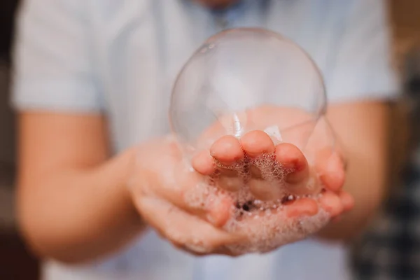 Küçük çocuk elinde baloncuk tutarak sakso çekiyor ve sabun köpüğü yapıyor. Makro