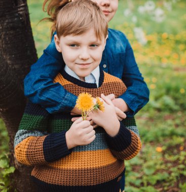 Küçük bir çocuk elinde karahindiba tutuyor ve tatlı bir kız arkada kalıp ona sarılıyor. Arkadaşlık kavramı