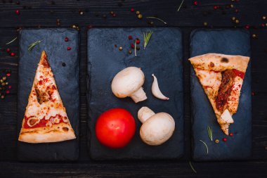 Taze kurutulmuş domatesli ev yapımı pizza, siyah taşlı arka planda tavuk, peynir ve biber.