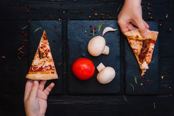 Taze kurutulmuş domatesli ev yapımı pizza, siyah taşlı arka planda tavuk, peynir ve biber.