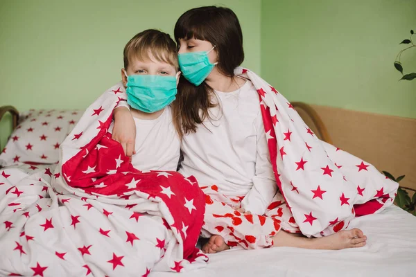 Sick boy and girl in medical masks are on duty under the covers
